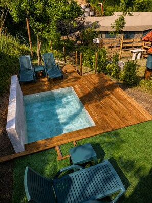 Eine Holzterrasse mit Swimmingpool, Liegestühlen und einem kleinen Tisch.