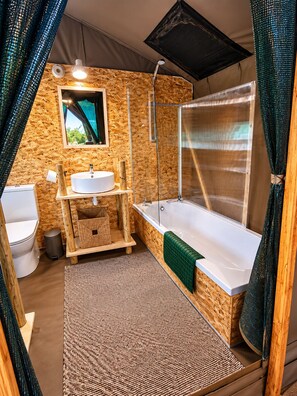 Ein kleines, rustikales Badezimmer mit Holzwand, Waschbecken, Toilette und Badewanne.
