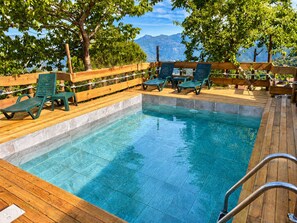 A pool area with wooden deck, green lounge chairs, and a view of mountains. - Safari Glamping Portugal Shark (Ventosa)