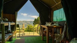 A tent with a dining table and chairs, a kitchen area, and a view of mountains. - Safari Glamping Portugal Shark (Ventosa)