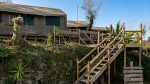 Un escalier en bois mène à un bâtiment doté d’une entrée abritée.