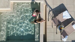 An aerial view of a swimming pool with clear water, surrounded by tiled flooring and a table with a drink and fruit. - Hotel Boutique Casa Romana Villa (Seville)