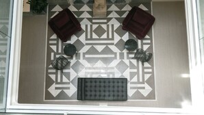 A top-down view of a hotel lobby with a patterned floor, a central seating area with a cushioned bench, two armchairs, and a small statue. - Hotel Boutique Casa Romana Villa (Seville)