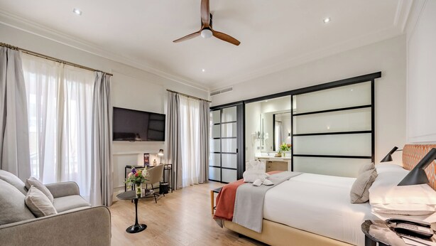 A modern hotel room with a bed, a sofa, a desk, and a TV. - Hotel Boutique Casa Romana Villa (Seville)