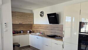 Une cuisine moderne avec des meubles en bois, un four encastré et un coin repas comprenant une table et des chaises.
