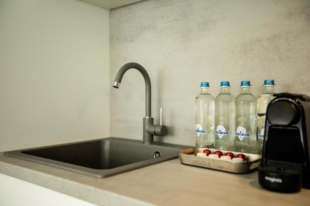 Een keukenzink met een moderne kraan, een schaal met aardbeien en diverse waterflessen.