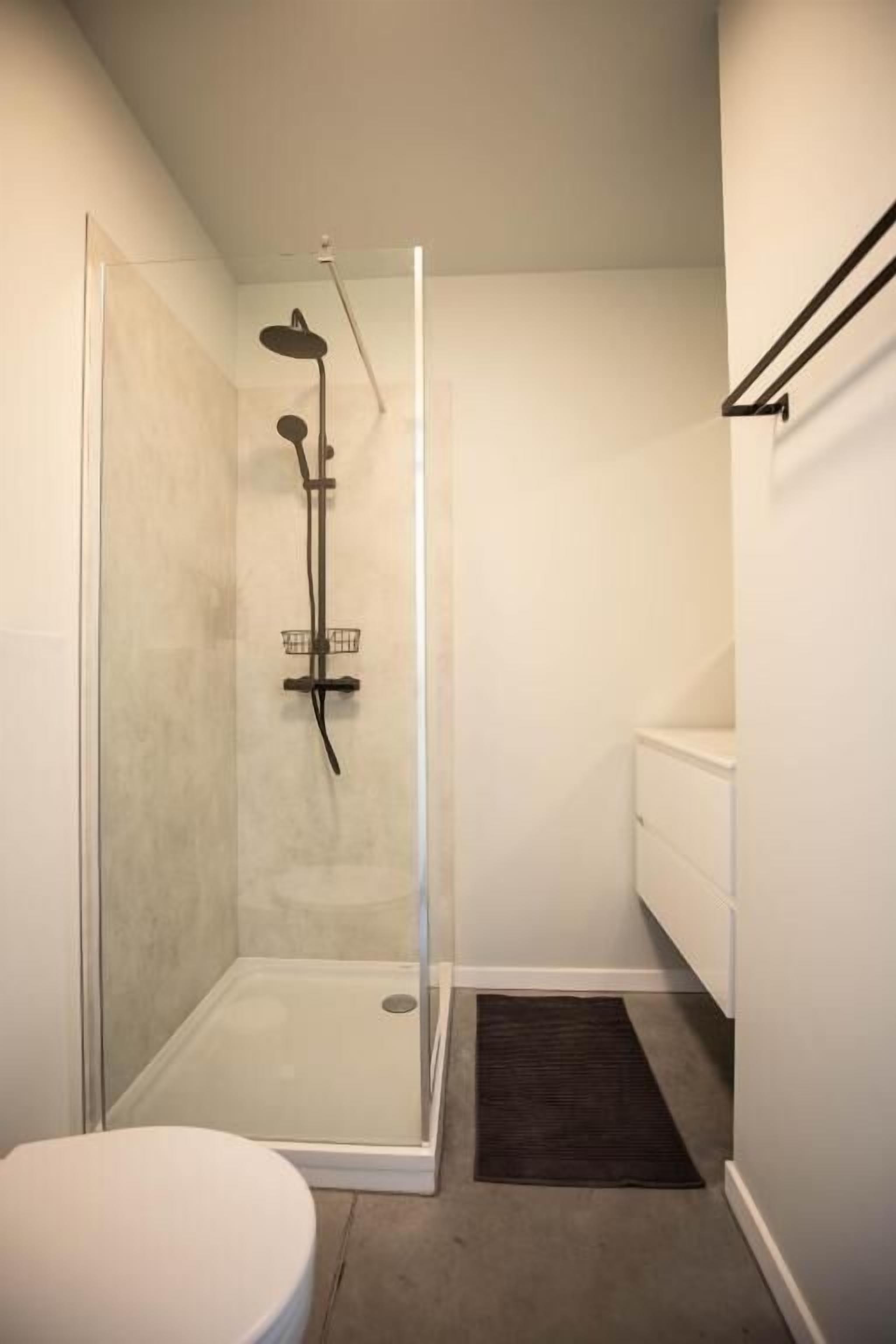 A modern bathroom with a glass-enclosed shower, a white toilet, and a white vanity.