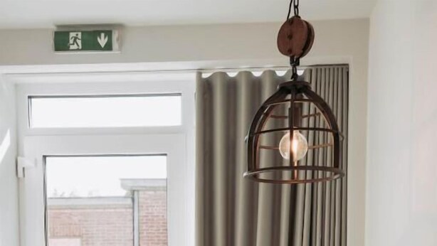 A dining area with a wooden table, a dark chair, and a hanging light fixture.
