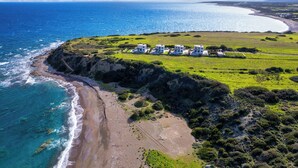 An aerial view of a coastal property with a beach, ocean, and a cluster of white buildings. - Aqua Natura Villas - Villa Beluga (Rhodes)