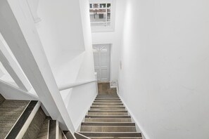 Eine schmale Treppe mit weißen Wänden und einem Holzgeländer.