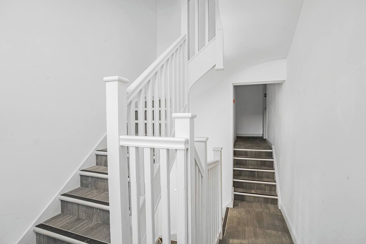 A staircase with white railings and wooden steps leading to a landing.