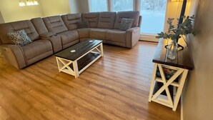 Un salon moderne avec un canapé d’angle, une table basse et une table d’appoint agrémentée d’une plante.