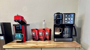 Une petite cuisine équipée d’une machine à café, d’une bouteille et de capsules de café sur le plan de travail.