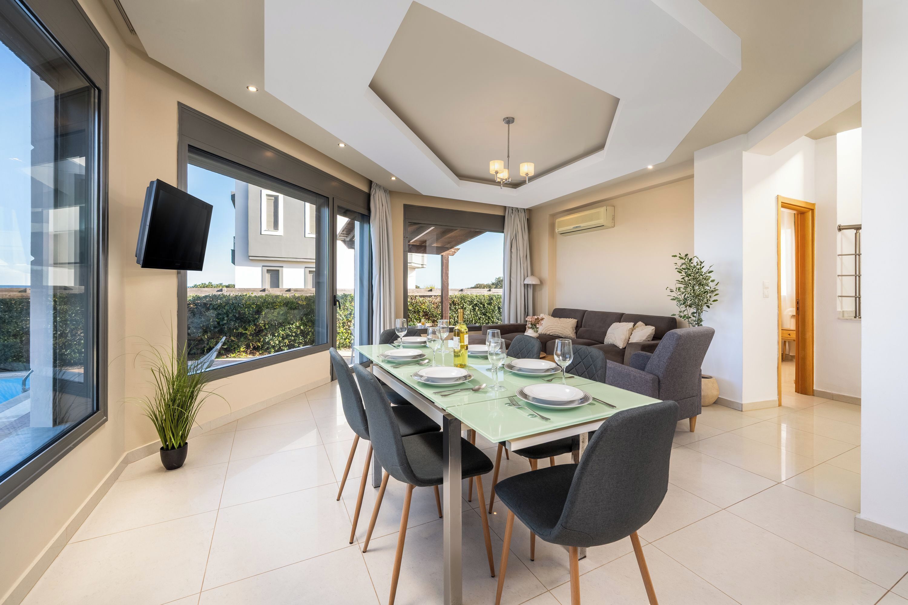 A modern dining area with a glass table, chairs, and a view of the outdoors.