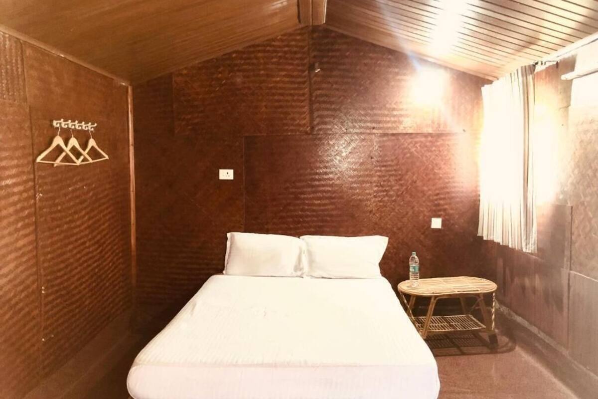 A wooden room with a bed, a small round table, and a wall-mounted towel rack.
