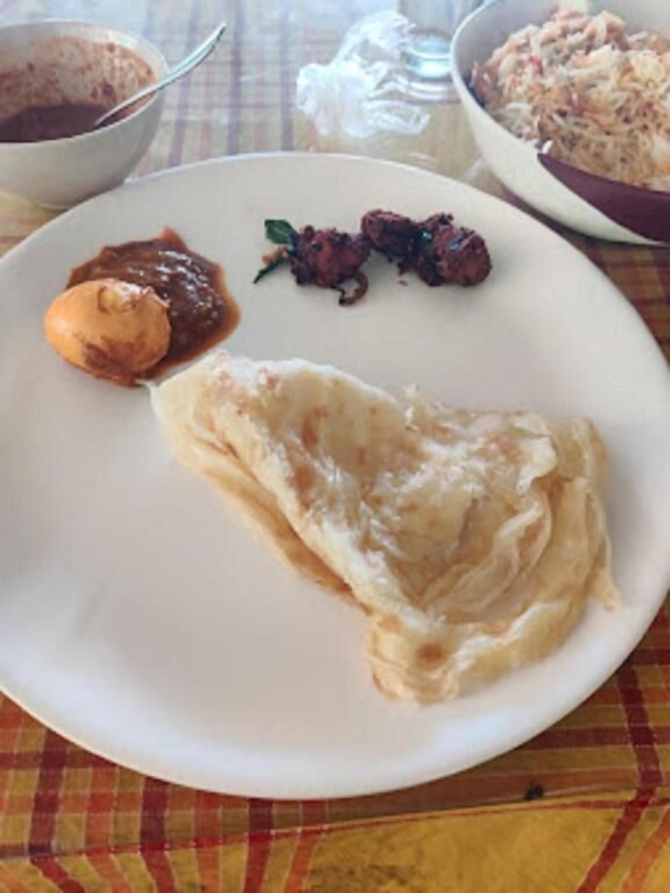 A plate with a piece of flatbread, a small dollop of chutney, and a few fried items.