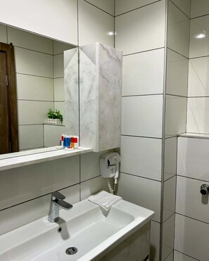 A bathroom with a white sink, a mirror, a towel rack, and a phone. - NITAWILLY HOTEL (Abuja)