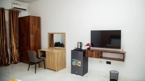 Una camera d'albergo con un letto, una scrivania, una televisione, un minibar e un armadio.