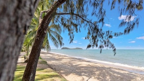 A beach with a clear view of the ocean, a sandy shore, and a distant island. - Bedrock Palm Cove I Private Pool I Sea Views I Family Retreat (Cairns)