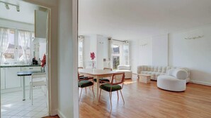Ein geräumiger Wohnbereich mit Holzboden, einem Esstisch mit Stühlen und einem weißen Sofa.