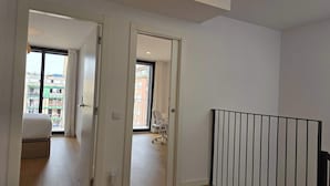 Ein modernes Apartment mit Holzboden, einem Balkon und Blick auf Gebäude.