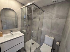 A modern bathroom with a glass-enclosed shower, a white sink, and a toilet. - Eixample Penthouse - Bright 2BR duplex & terraces (Barcelona)