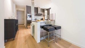 Una cocina moderna con una isla central, electrodomésticos de acero inoxidable y taburetes negros.