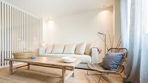 Una sala de estar moderna con una mesa de centro de madera, un sofá blanco y una silla de mimbre.