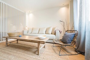 A modern living room with a wooden coffee table, a white sofa, and a wicker chair. - The Double Loft | Designer Loft for 4 Next to Atocha (Madrid)