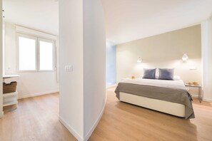 A bedroom with a bed, bedside tables, a window, and a wall-mounted light fixture. - The Double Loft | Designer Loft for 4 Next to Atocha (Madrid)
