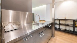 Una cocina moderna con electrodomésticos de acero inoxidable, un lavamanos y una cesta de alambre en la encimera.