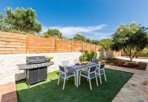 An outdoor patio with a grill, dining table, and chairs. - Primavera Villa - 2 Heated Pools & Jacuzzis (Pagkalochori)