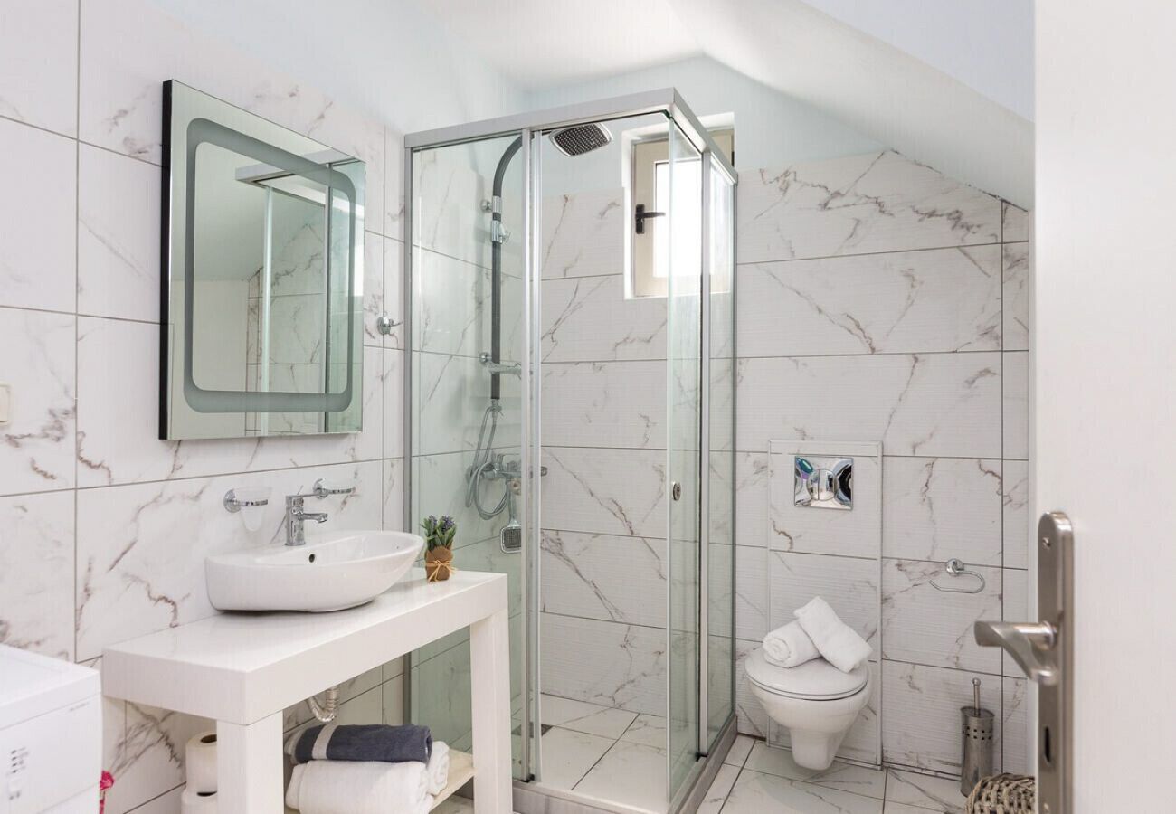 Un bany modern amb dutxa envidriada, un vàter blanc i un lavabo.