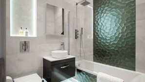A modern bathroom with a glass-enclosed shower, a round sink, and a decorative wall panel.