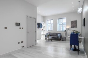 Een moderne woonkamer met een bank, salontafel en een eethoek met een stoel.