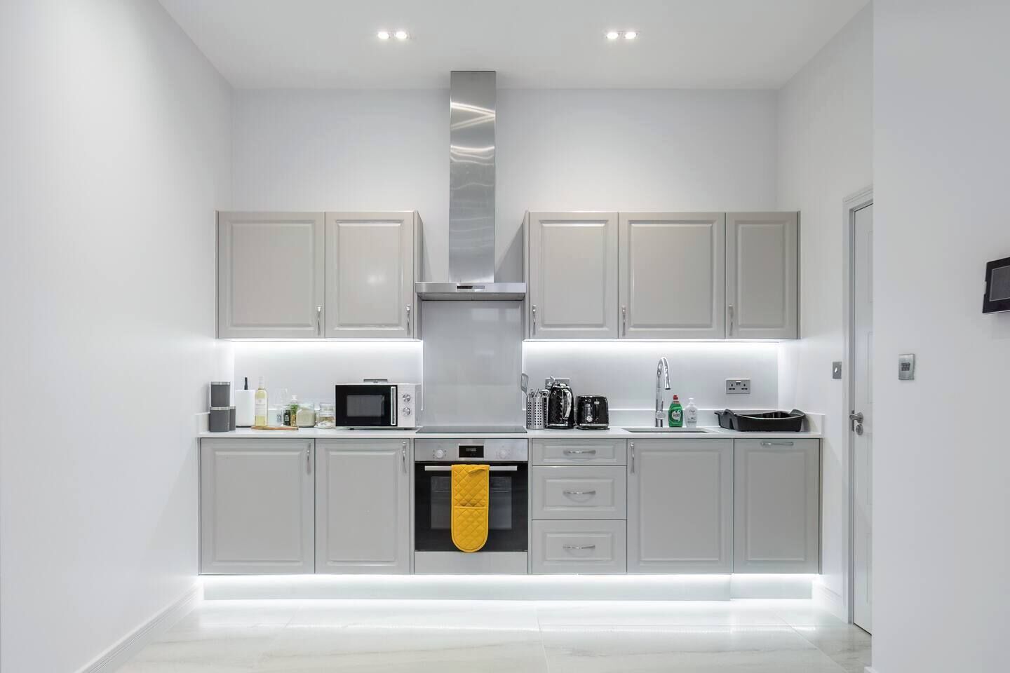 Una cocina moderna con gabinetes grises, una campana de acero inoxidable y un horno integrado.