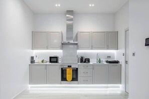 Een moderne keuken met grijze kastjes, een roestvrijstalen afzuigkap en een inbouwoven.