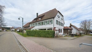 Una casa de dos pisos con techo inclinado, un sendero empedrado y un farol.