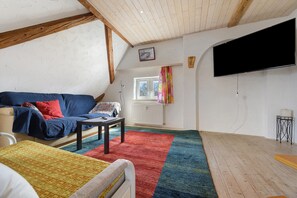 Een gezellige woonkamer met een bank, een salontafel, een televisie en een raam met gordijnen.