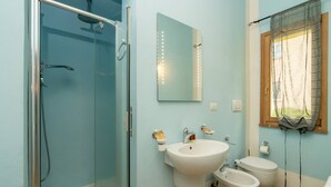 A bathroom with a glass-enclosed shower, a sink, a bidet, and a toilet.