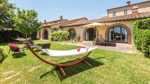 A house with a patio, outdoor seating, and a hammock. - Villa Aquila-cignella Resort Acommodation Tuscany (Trequanda)