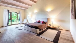 A bedroom with a large bed, a wooden ceiling, and a view of greenery through a window. - Villa Aquila-cignella Resort Acommodation Tuscany (Trequanda)