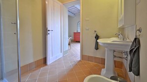 Ein Badezimmer mit weißem Waschbecken, einem Spiegel und einer Duschkabine.