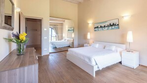 Un dormitorio moderno con una cama grande, mesitas de noche, un espejo y un cuadro en la pared.