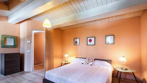 Ein Schlafzimmer mit einem Bett, zwei Nachttischen mit Lampen, einer Kommode und einer Tür zu einem anderen Raum.