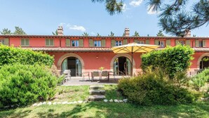 Un edificio rosso con portali ad arco e un patio arredato.