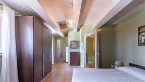 Una camera da letto con un letto grande, un'armadio in legno e un corridoio che porta ad altre stanze.