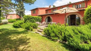A red villa with a patio, outdoor furniture, and a well-maintained garden. - Villa Limone - 3 Bedroom Villa in Tuscany (Trequanda)