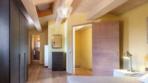 A modern bedroom with a wooden ceiling, a large bed, a bedside table with a lamp, and a wardrobe. - Villa Limone - 3 Bedroom Villa in Tuscany (Trequanda)