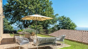 Een terras buiten met een tafel, stoelen en een bank.